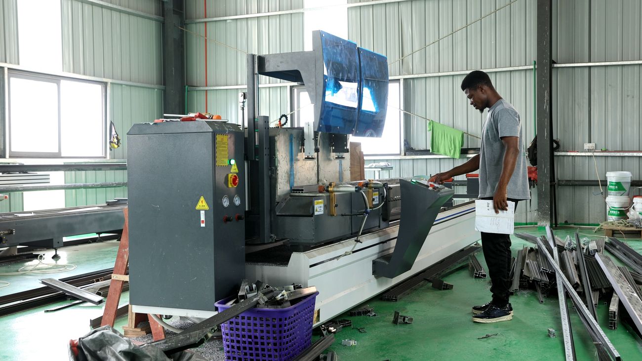 Worker operating a CNC aluminium cutting machine
